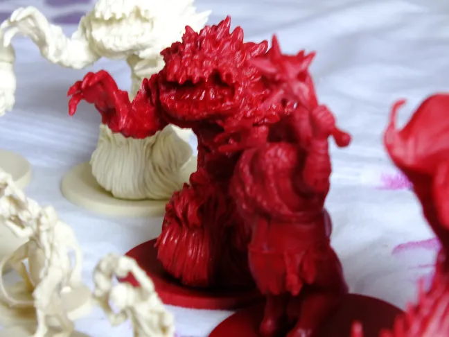 Descent hero and monster miniatures: heroes, cream creatures and red demons with a dragon · 2